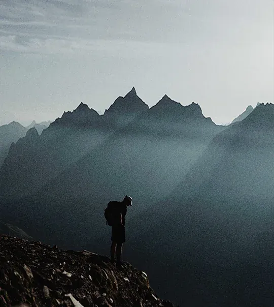Hiker standing on a rocky ridge in front of jagged peaks near the Großglockner