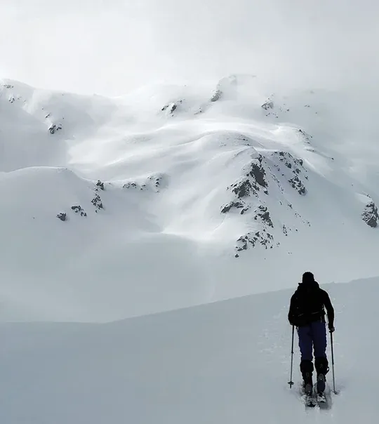 Ski tourer climbing a snowfield towards rocky peaks in Kaunertal